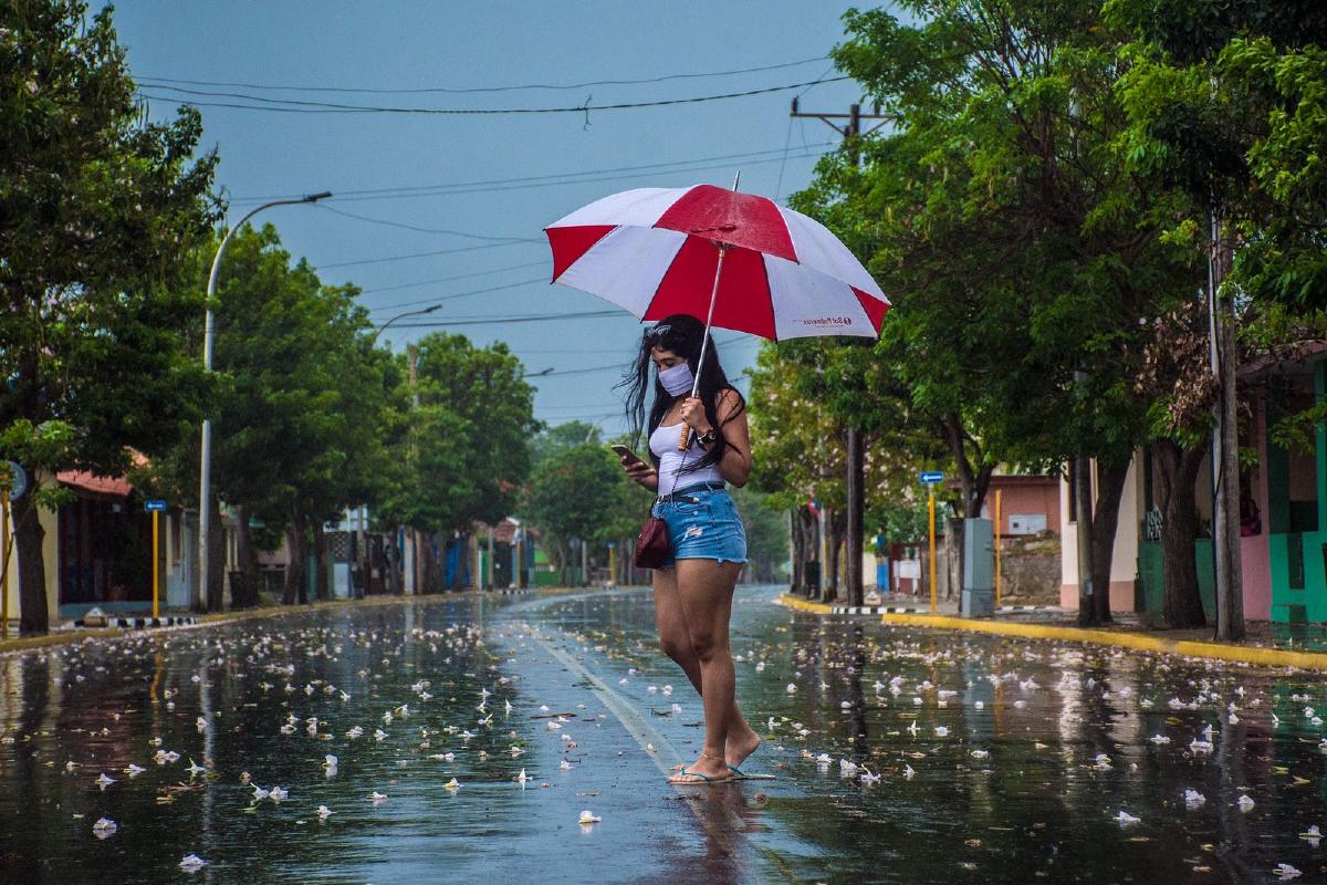 a woman with a cell phone walks connected to the Internet on a street in Cuba.