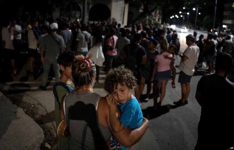 Una madre carga a su hijo durante una protesta en el Vedado